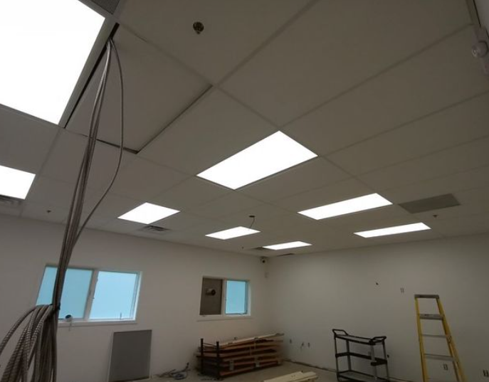 Interior view of a room with ceiling lights, windows, and construction materials.