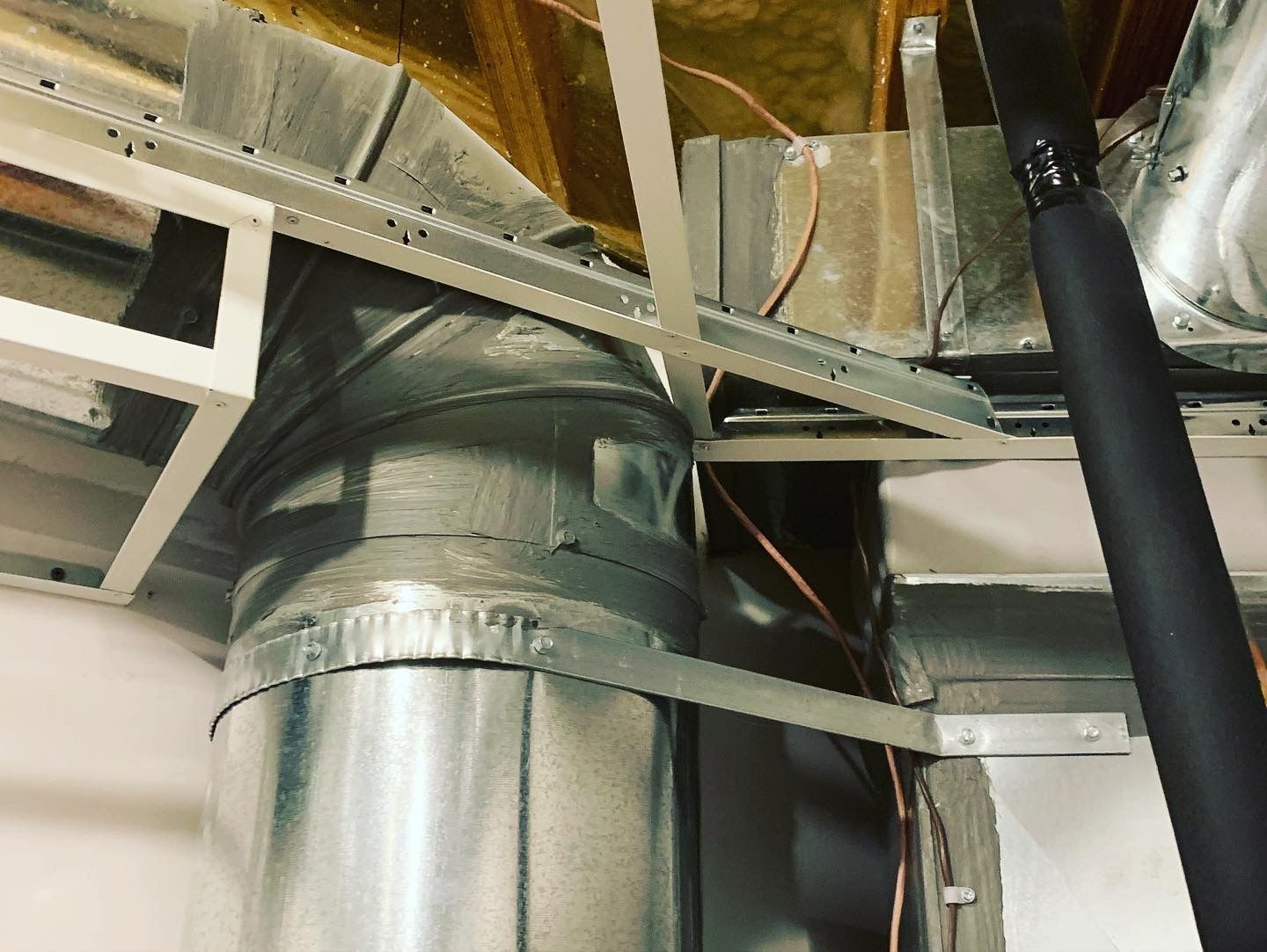 Metal ductwork and framing against a light-colored wall and ceiling, with insulation visible above.