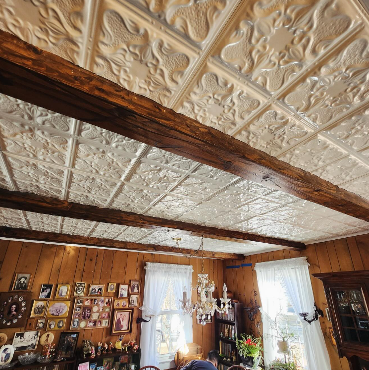 Decorative tin ceiling with exposed wooden beams; dining room interior.