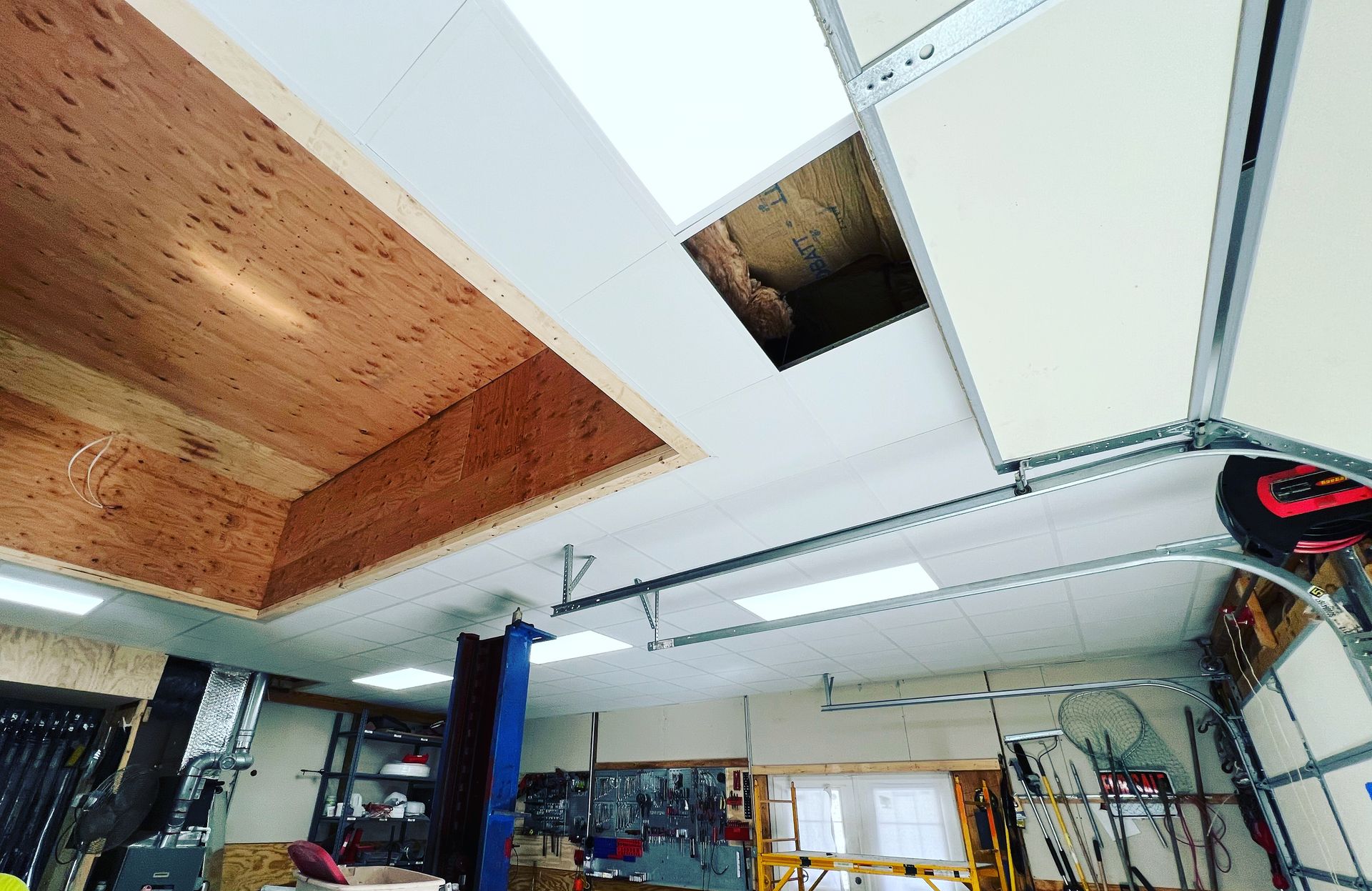 Garage ceiling under construction, with wood paneling, open hole, and metal tracks.