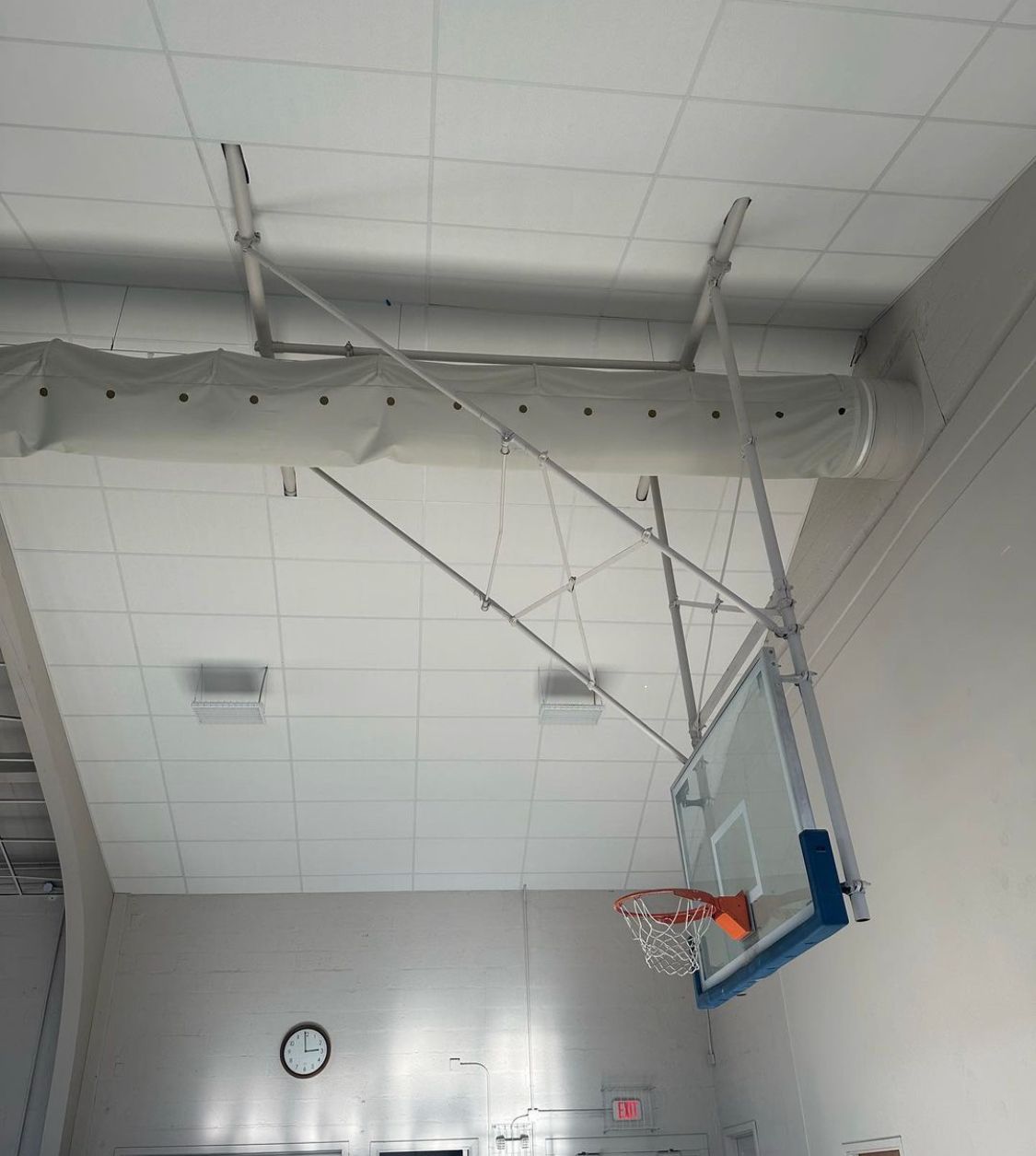 Basketball hoop mounted on a white ceiling in a gymnasium.