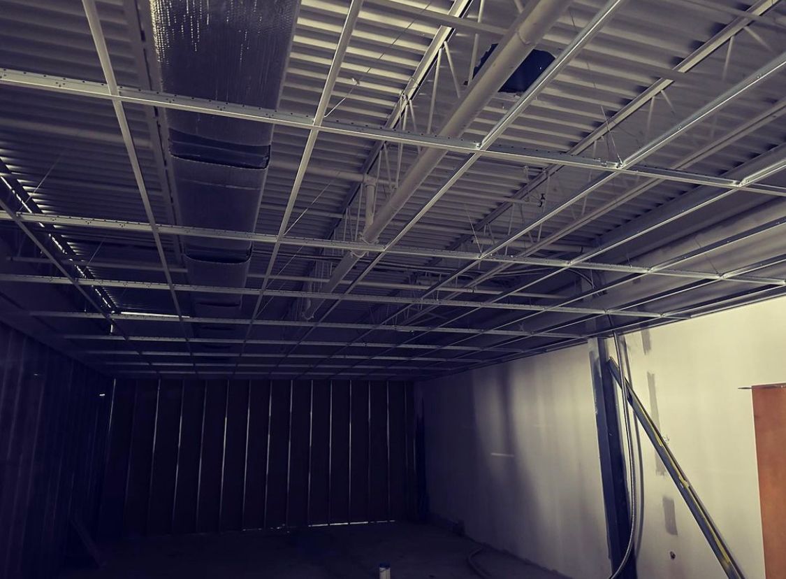 Metal ceiling framework under construction in a hallway. Walls are partially finished.
