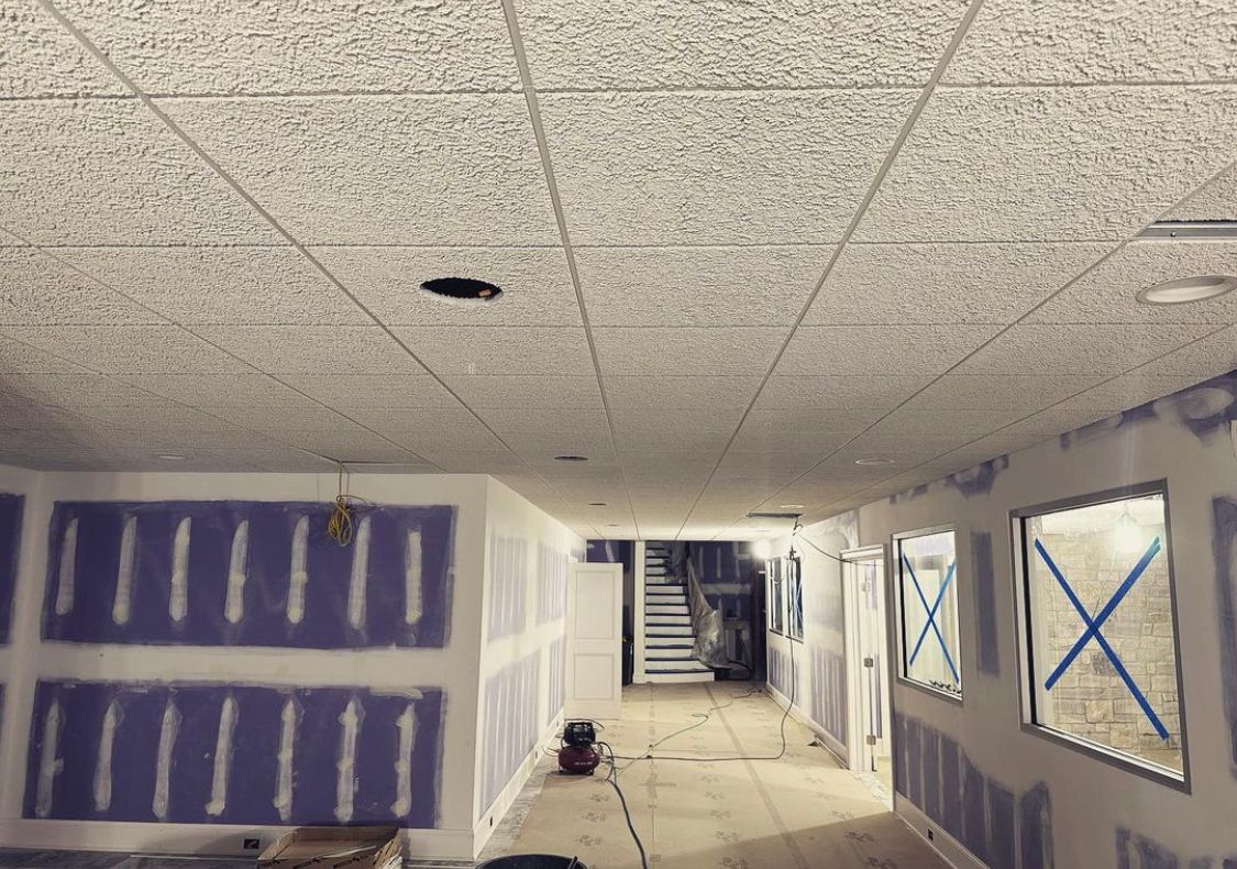 Interior under construction, drywall, acoustic tile ceiling, and partially finished walls.
