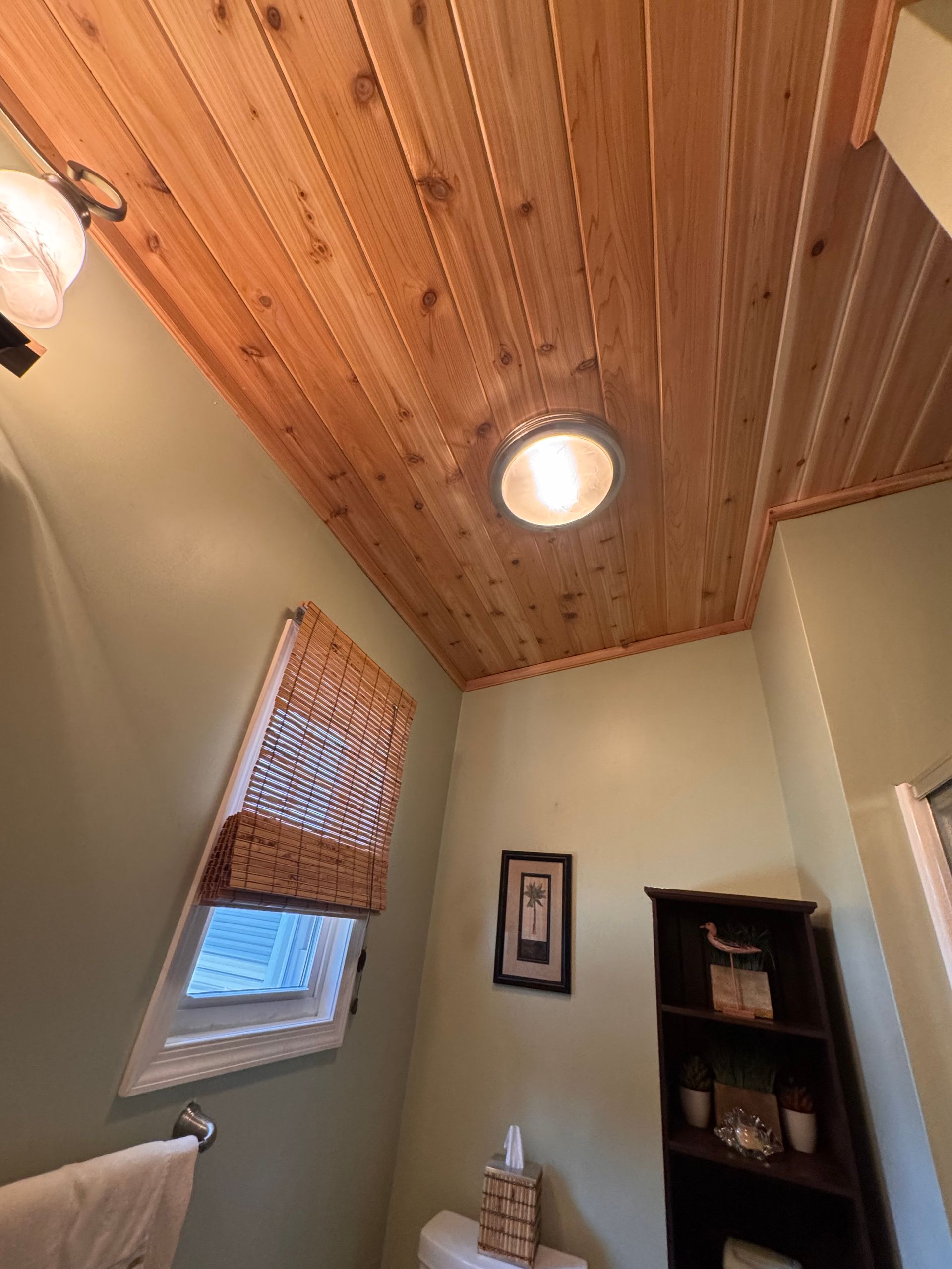 Bathroom with wood-plank ceiling, green walls, woven window shade, and recessed light.