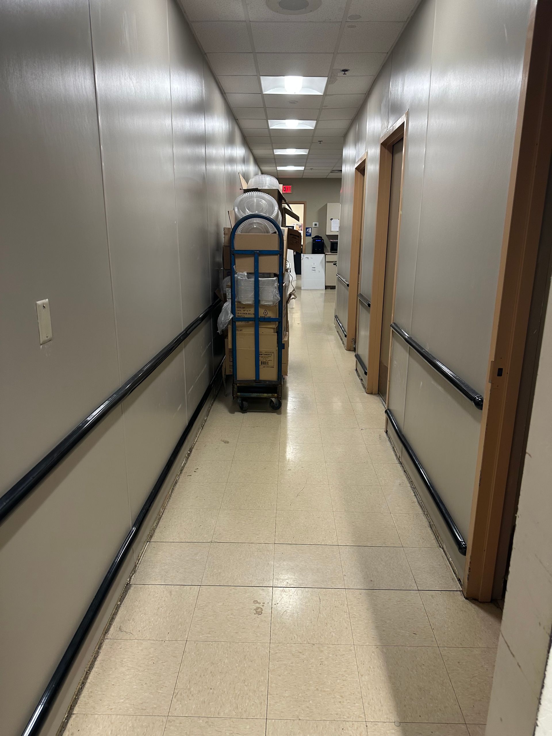 Hallway with cart of boxes, handrails, and doors.