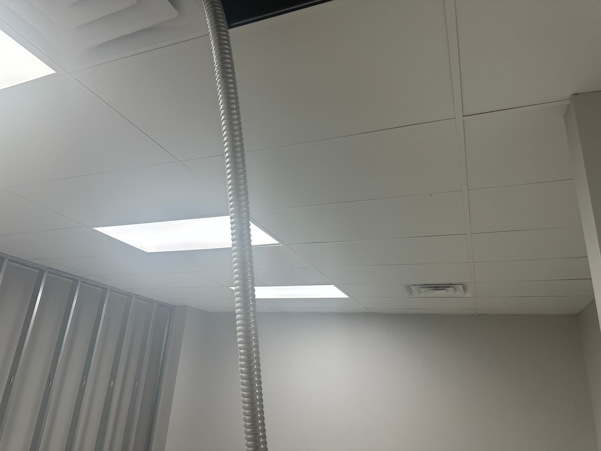 Ceiling with lights and a flexible silver vent pipe hanging down.