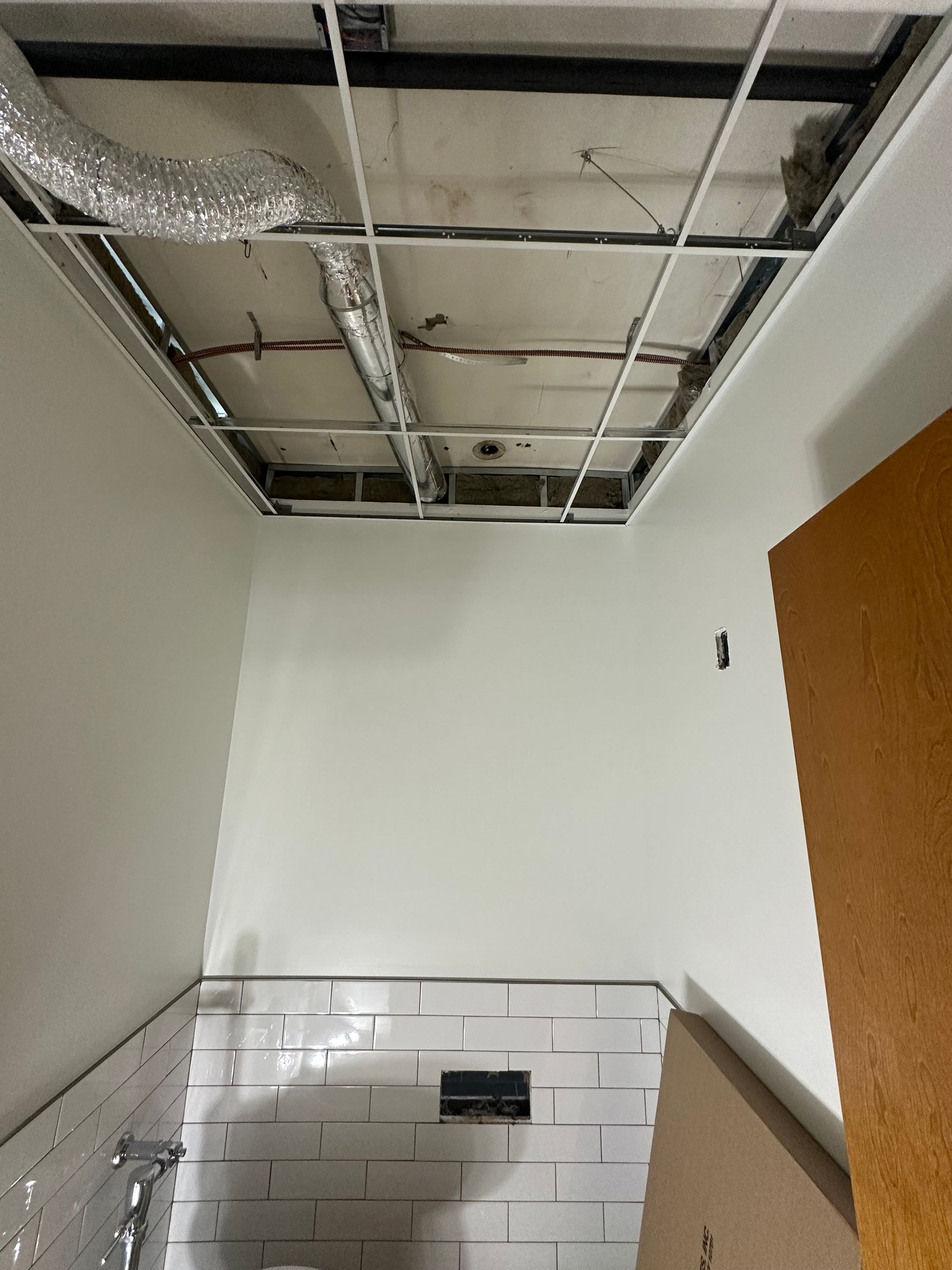 Interior view of unfinished ceiling with exposed grid, walls, and doorway.