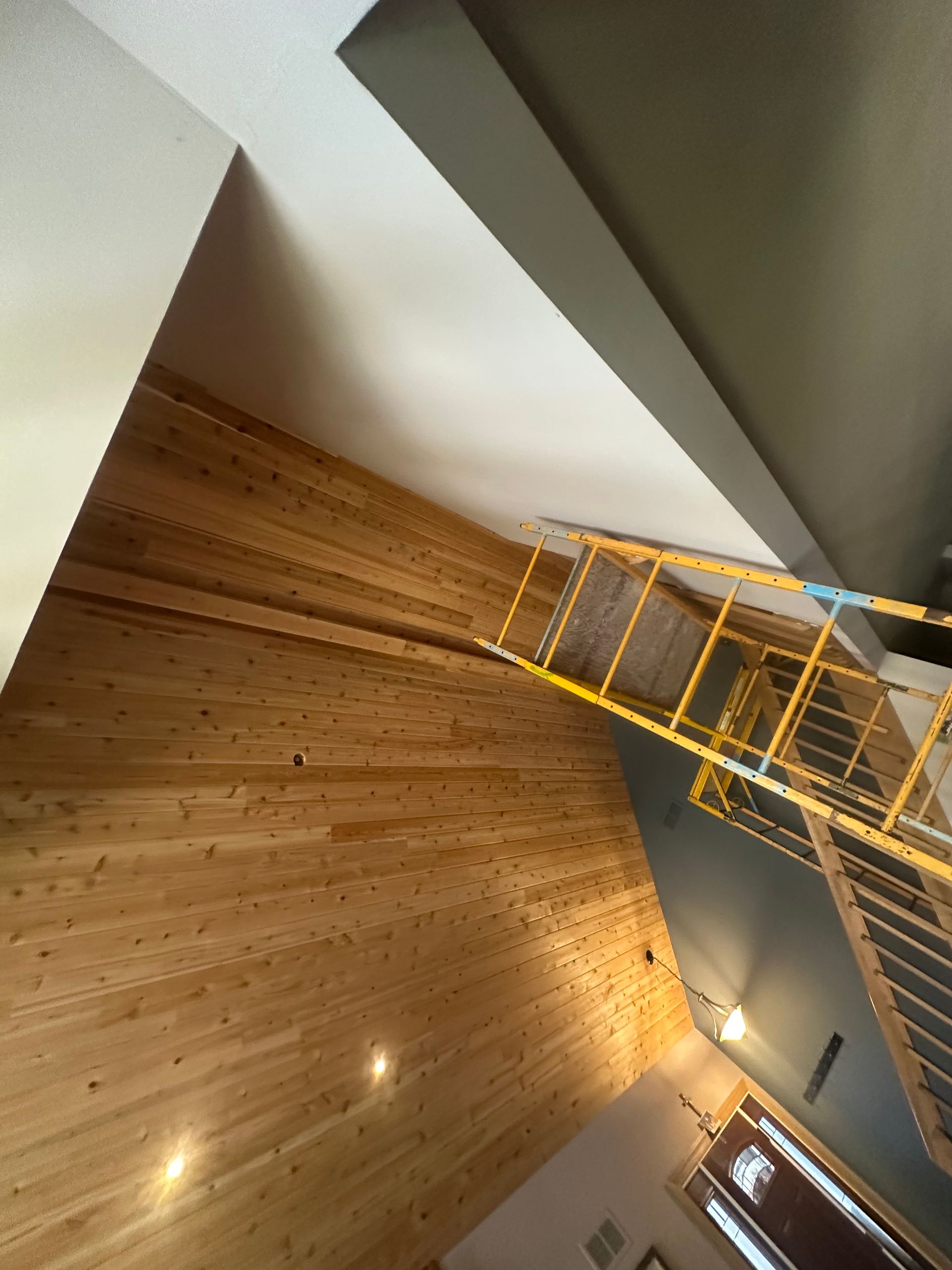 Wood-paneled wall and white ceiling with a yellow scaffold. Interior view, construction in progress.