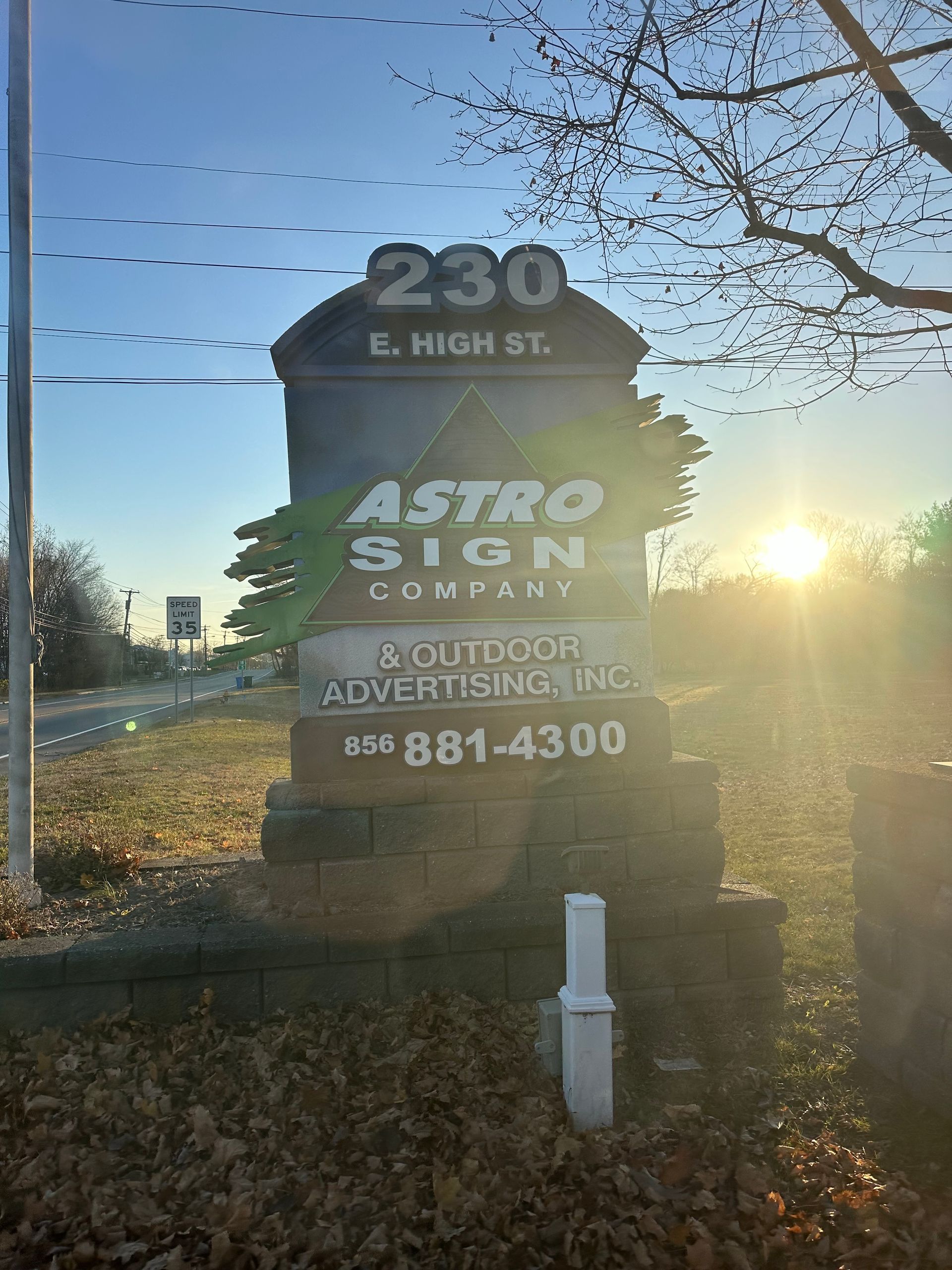 Sign for Astro Sign Company at 230 E. High St. in front of a setting sun.