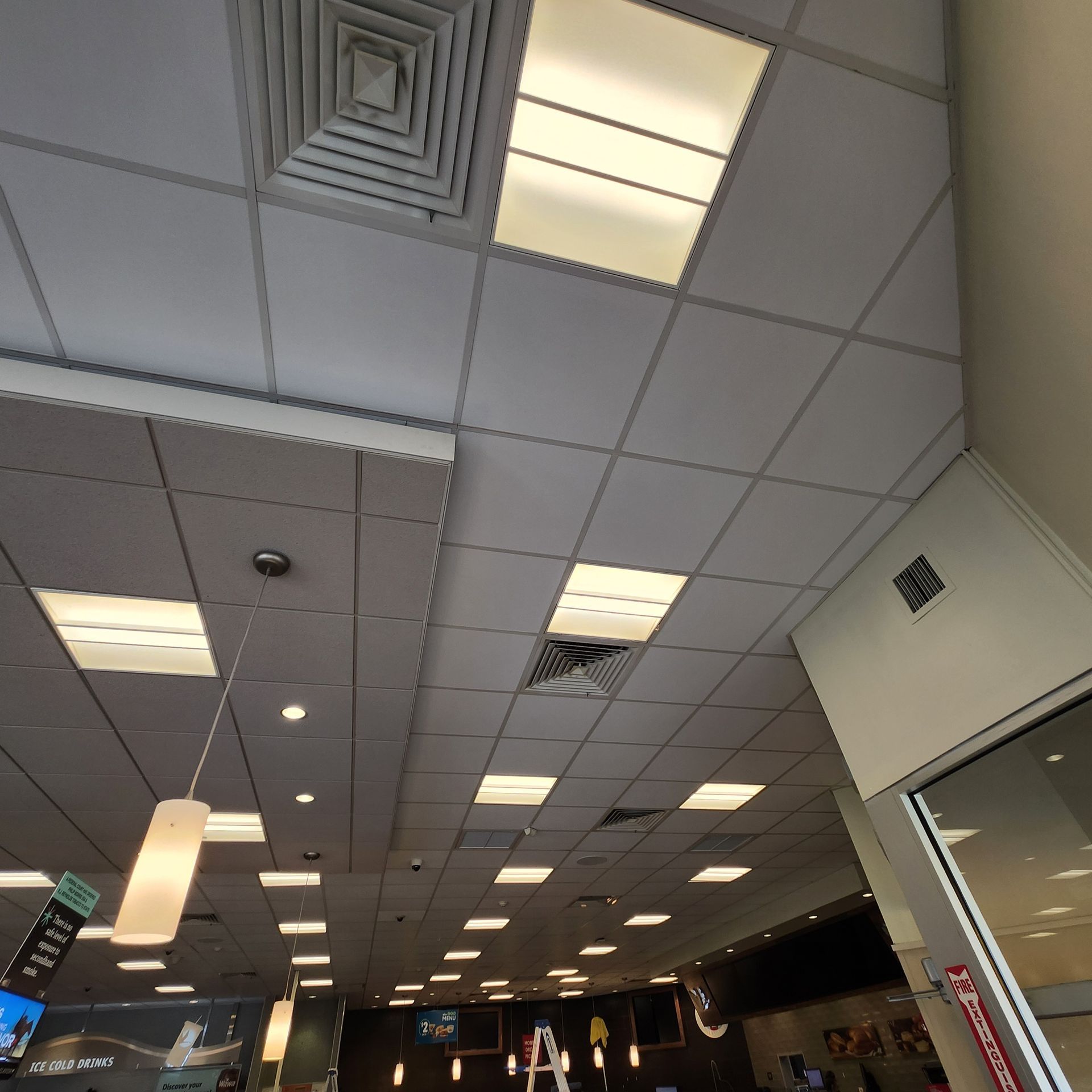 Ceiling of a brightly lit commercial space with various lights and ventilation.