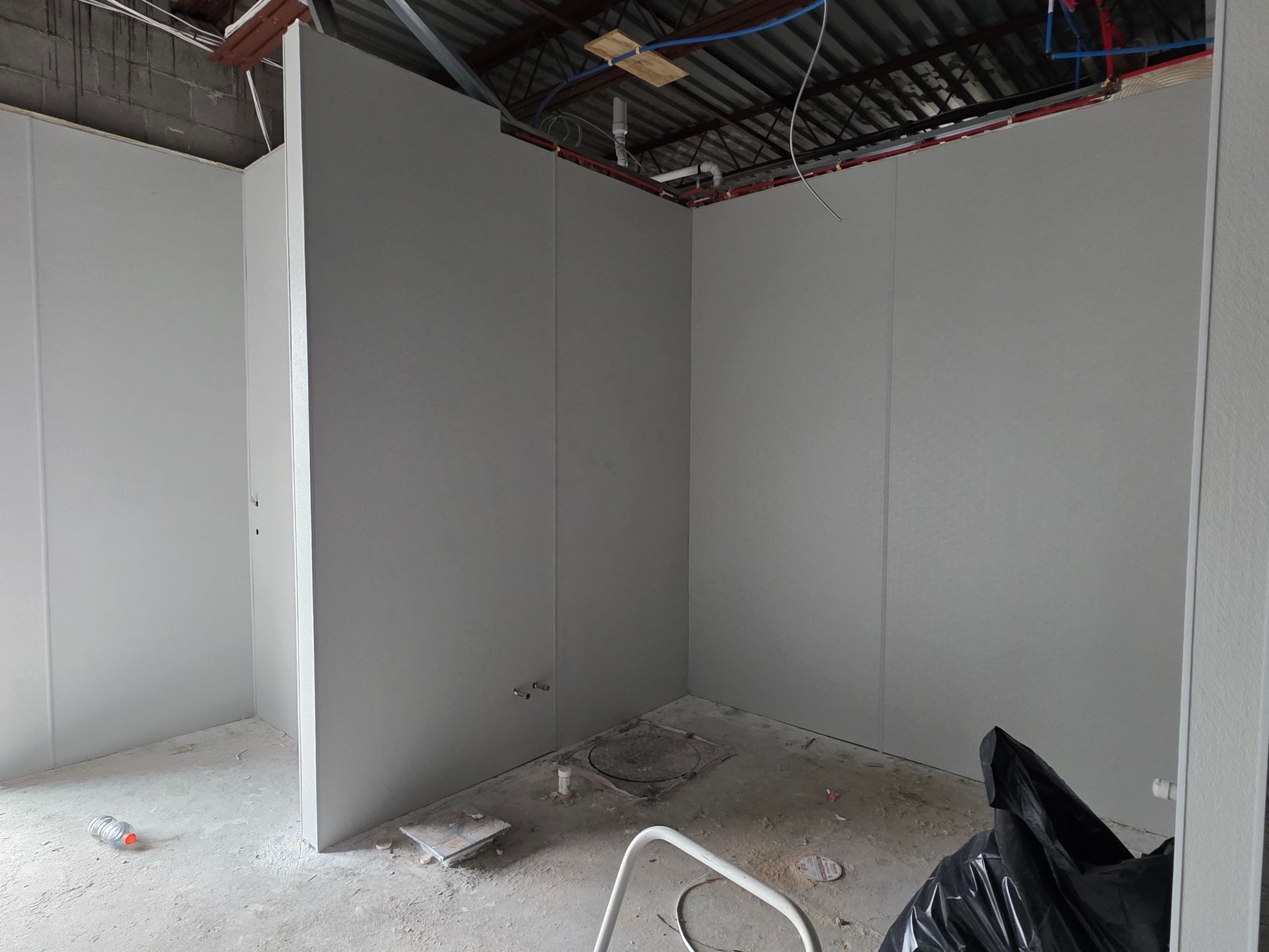 Interior view of a room under construction with gray wall panels installed. 