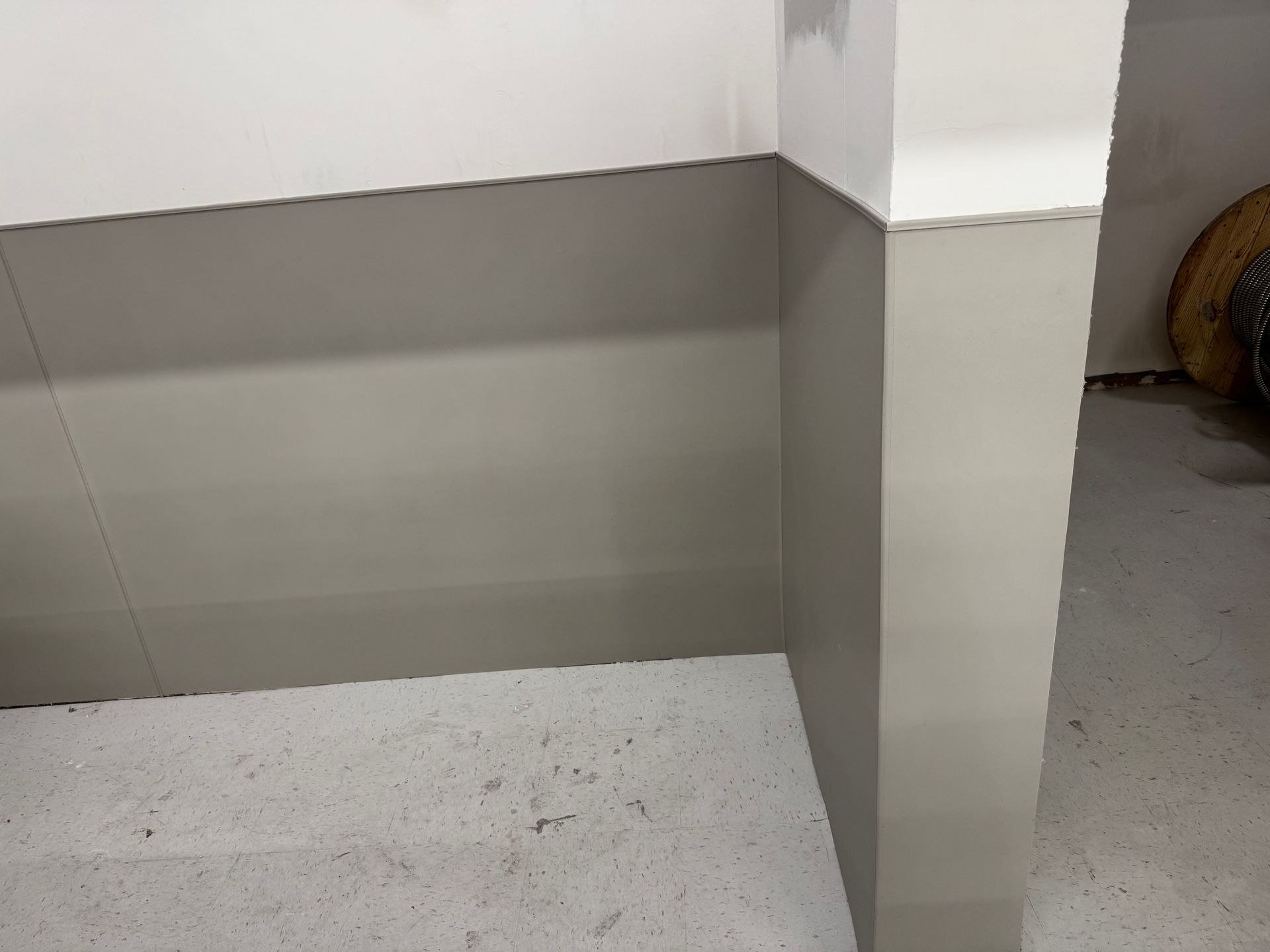 Corner of a room with white and gray walls, a concrete floor.