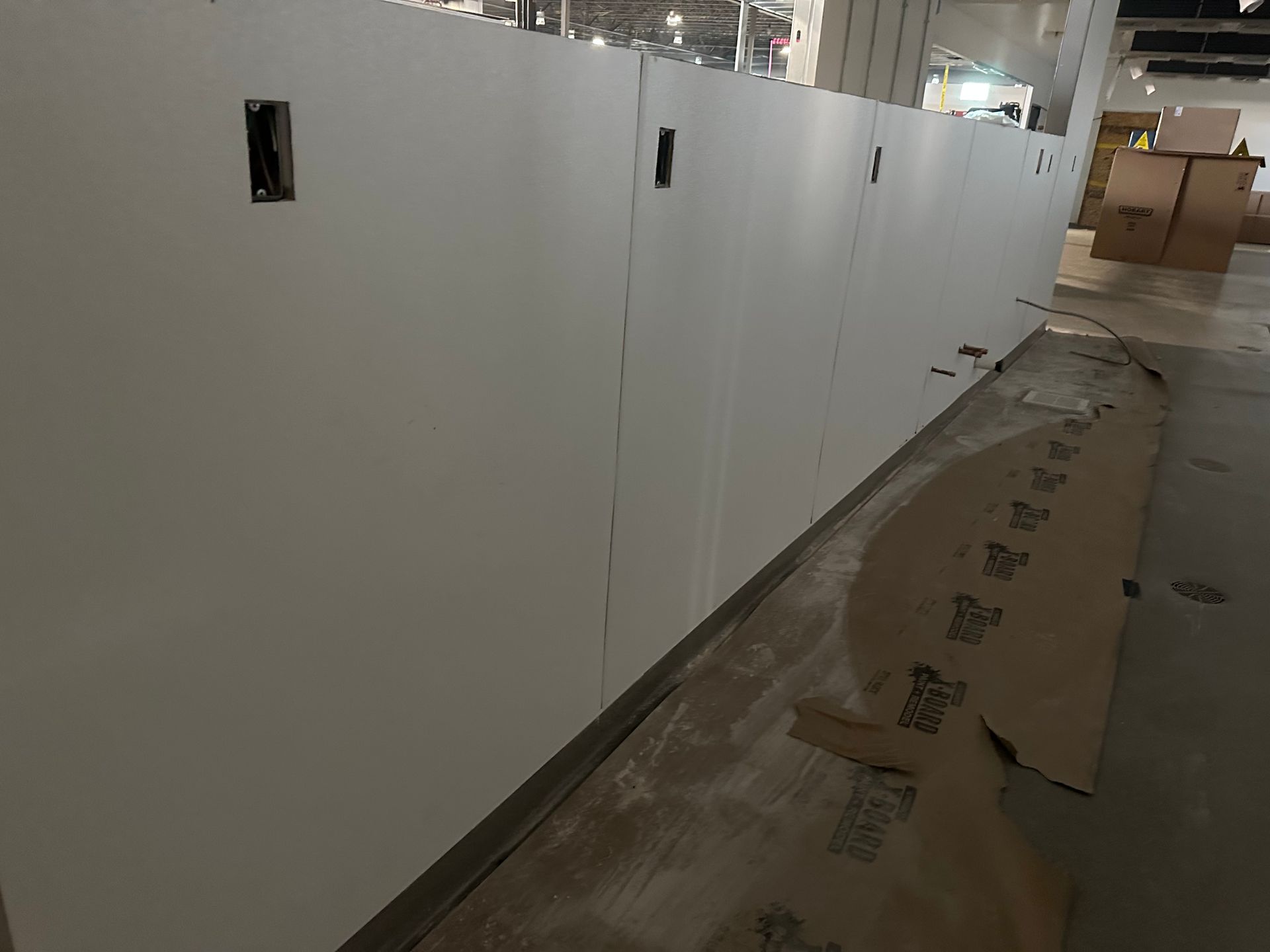 White wall under construction with electrical outlets; boxes in the background.