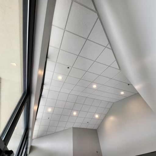 White tiled ceiling with recessed lights, angled walls, and a large window.
