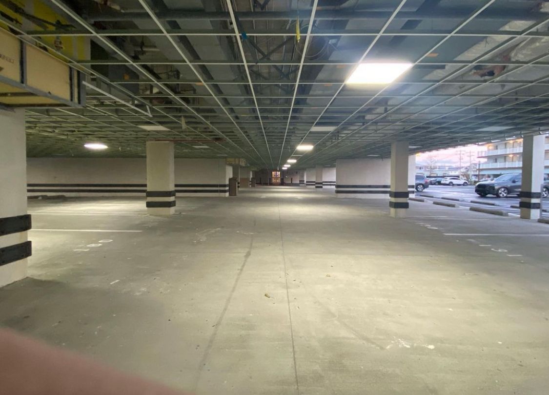 An empty, well-lit parking garage with concrete floor and support columns.