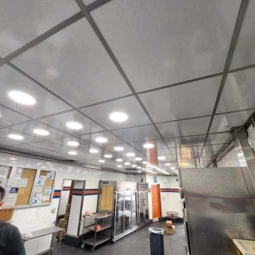 Restaurant interior with a bright ceiling and stainless steel kitchen equipment.