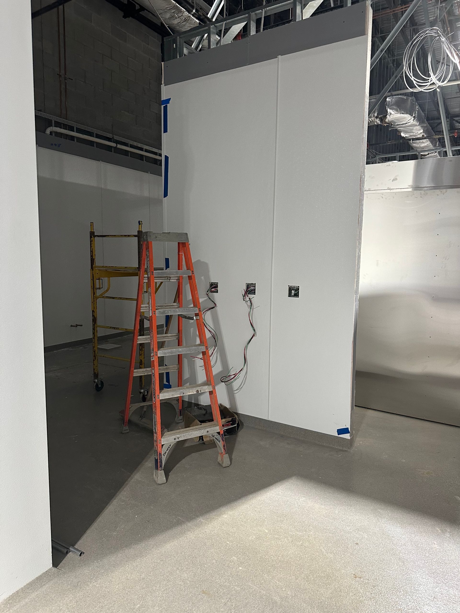 Construction site interior with ladders and unfinished walls.