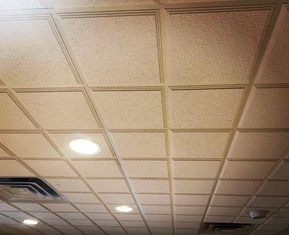 Beige drop ceiling with recessed lighting and air vents.