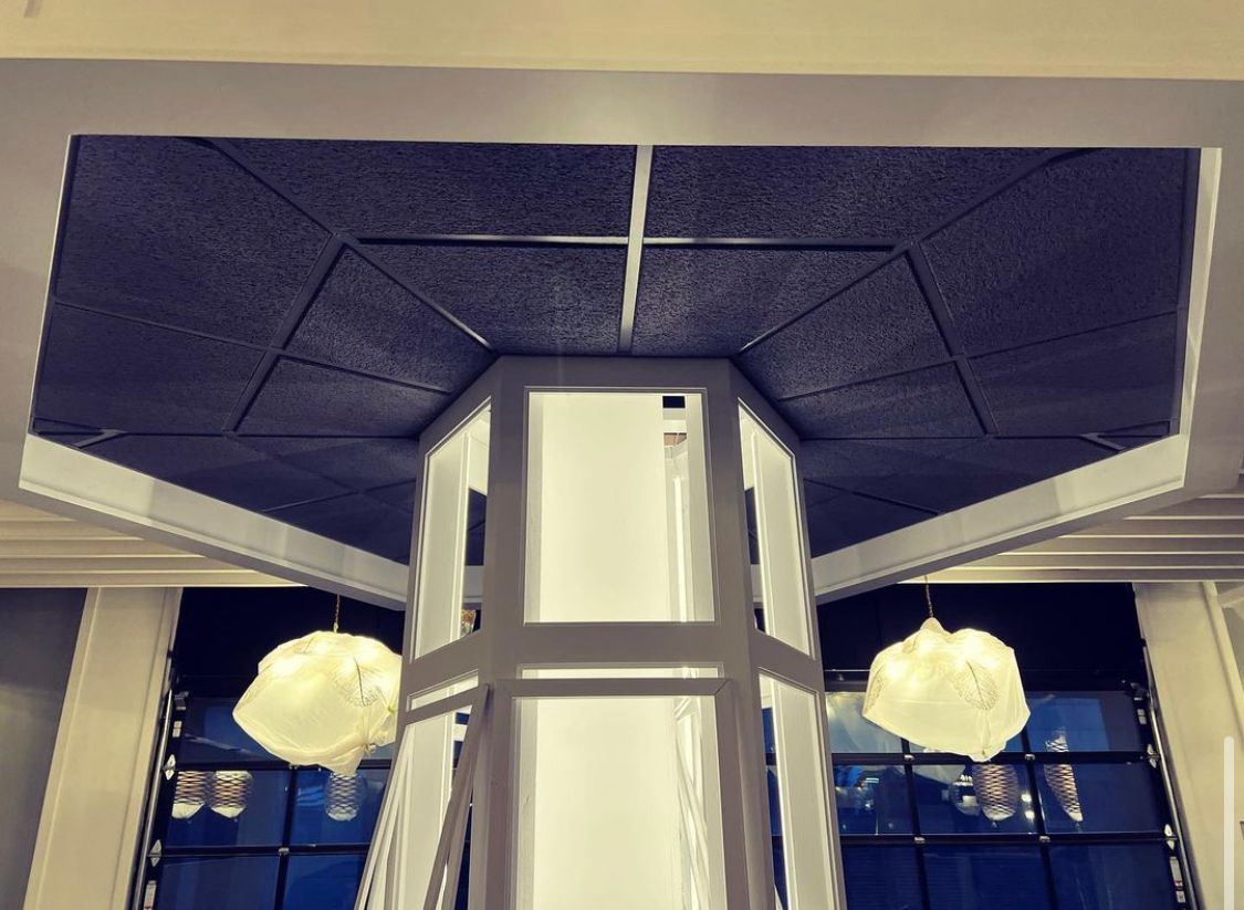 Geometric ceiling with a central, illuminated structure. Two globe-shaped lights hang below.