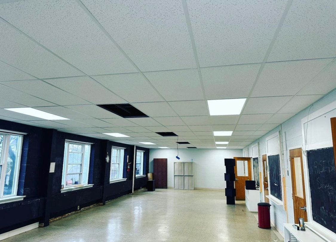 Long empty room with windows, ceiling lights, and reflective floor.