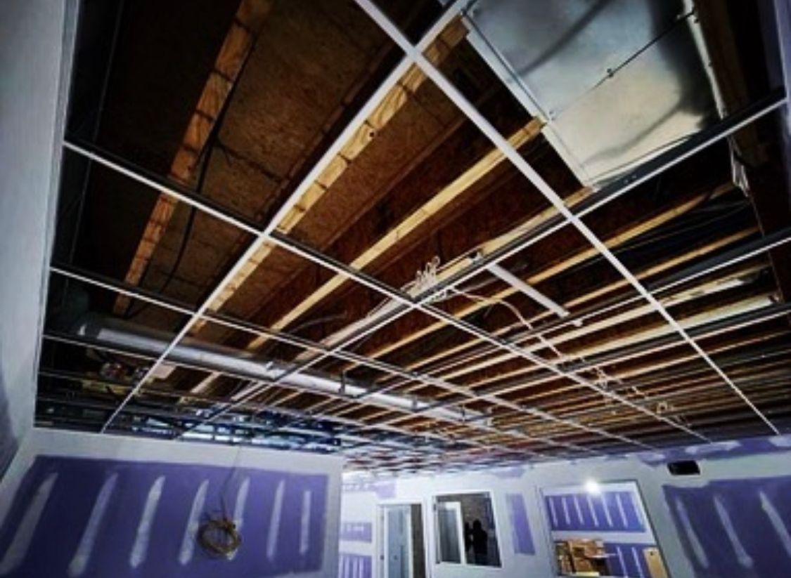 Ceiling framework with exposed beams and unfinished drywall in a room.