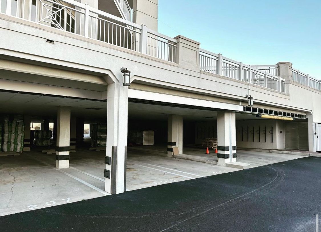 Exterior view of an open-air parking structure with concrete pillars and a low clearance.