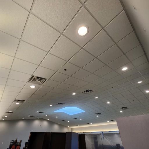 Suspended ceiling with recessed lights, vents, and a skylight in a commercial interior.
