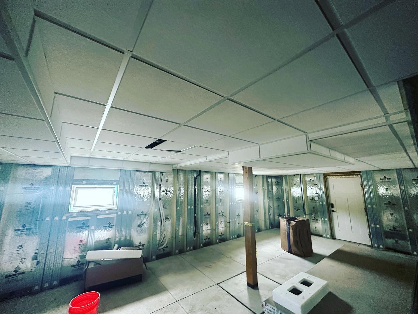 Basement under construction, with new ceiling, walls, and a window.
