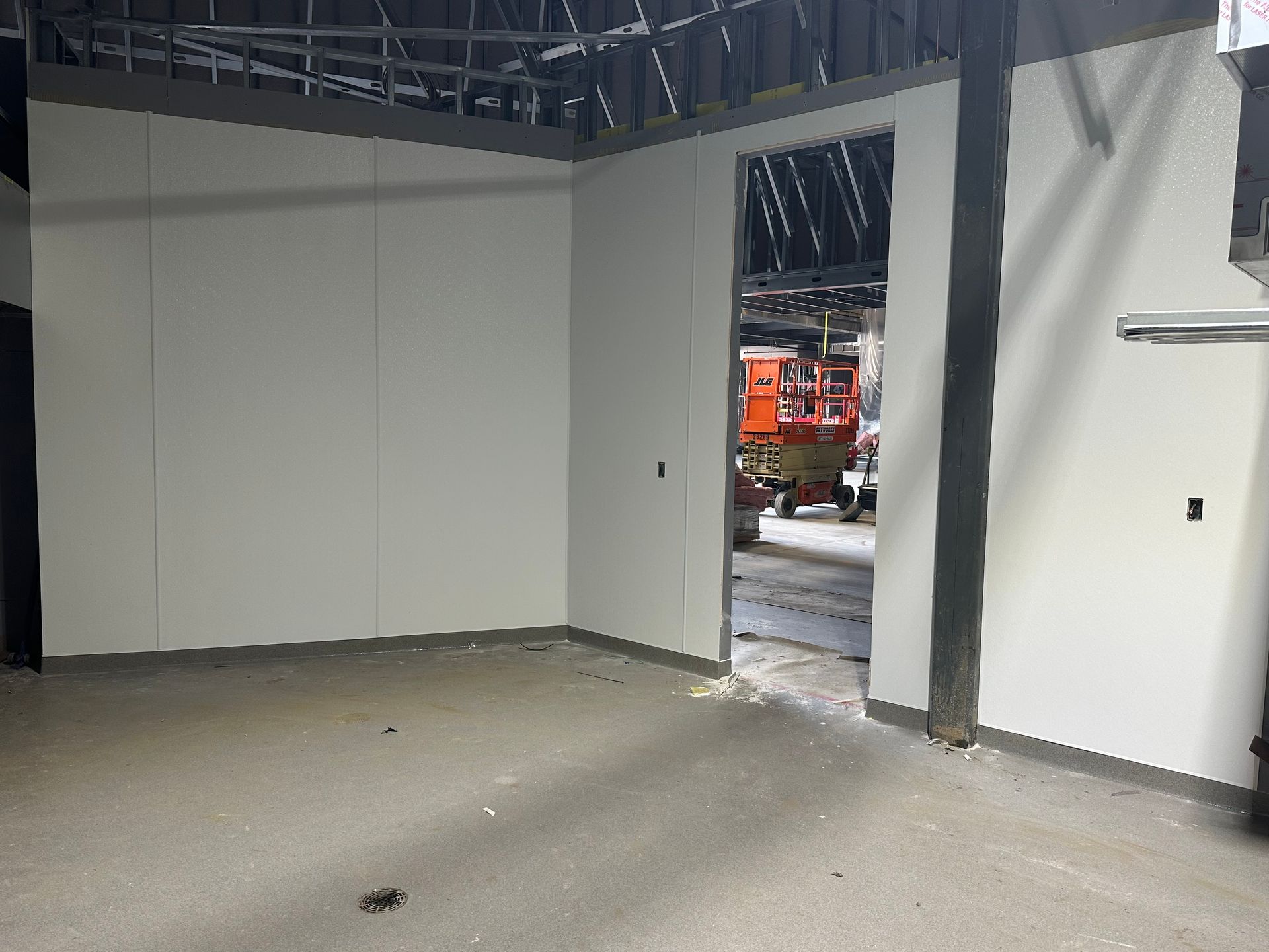 Interior room with light-colored walls, doorway, and concrete floor under construction