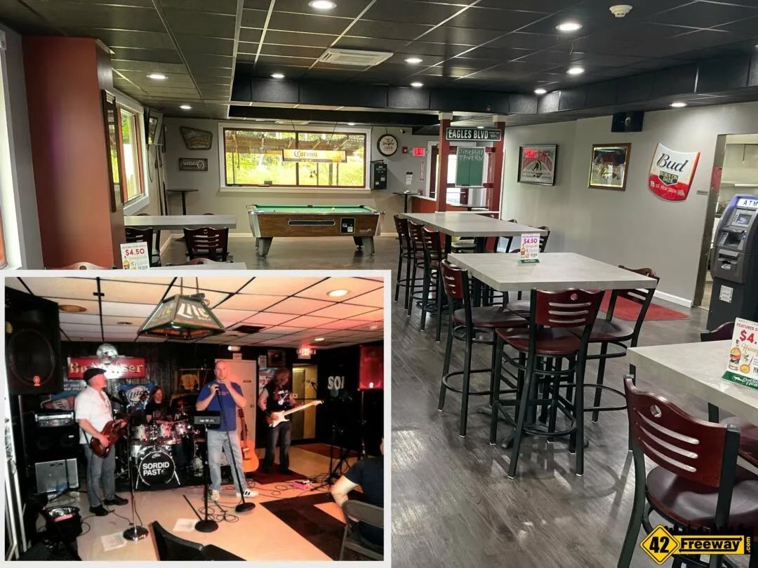 Bar interior with tables, pool table, and a band performing on a stage.