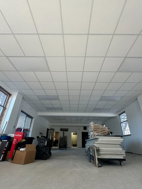 Empty room with white tile ceiling and stacks of materials.