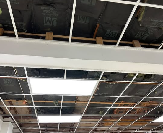 Exposed ceiling with metal grid, wooden beams, insulation, and recessed lights.