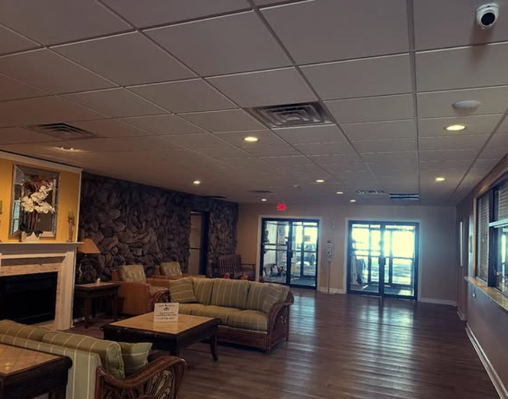 Lobby with couches, fireplace, stone wall, and glass doors to outdoors.