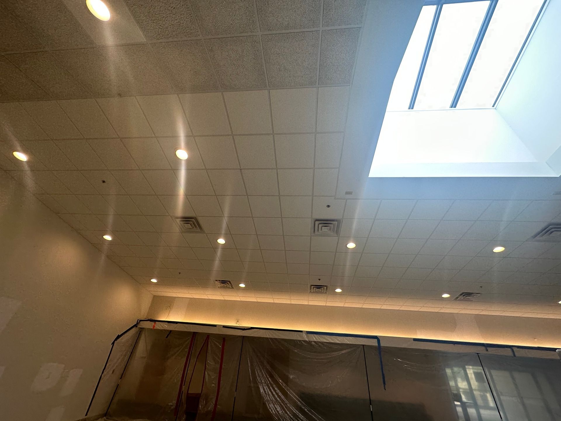 White ceiling with recessed lights, air vents, and a skylight. 