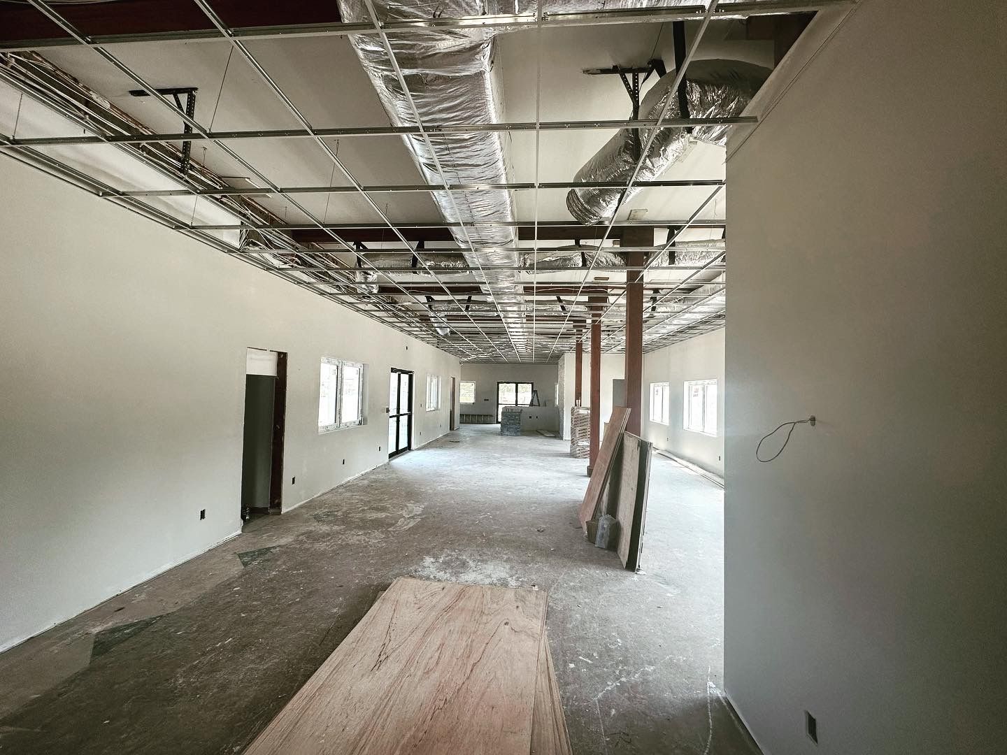 Interior of a building under construction, showing walls, ceiling with ductwork, and concrete floor.