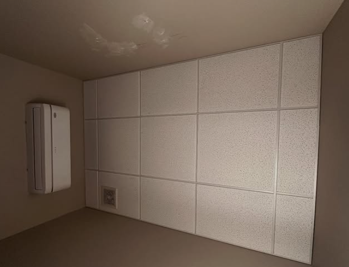 White square tiled wall with an air conditioning unit and outlet.