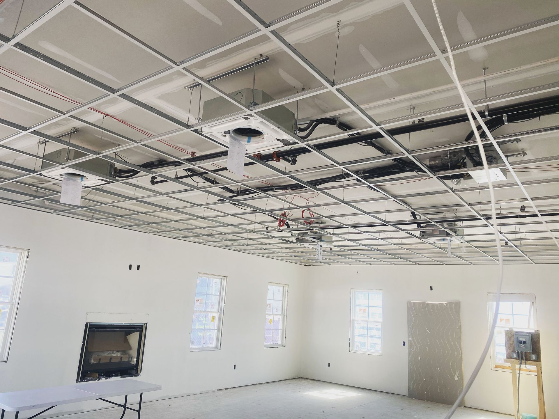 Unfinished room with drywall, ceiling grid, electrical and HVAC components exposed.