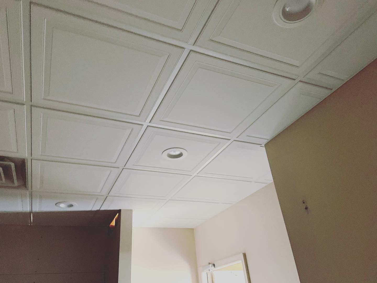 White, square ceiling tiles with recessed lighting in an interior space.