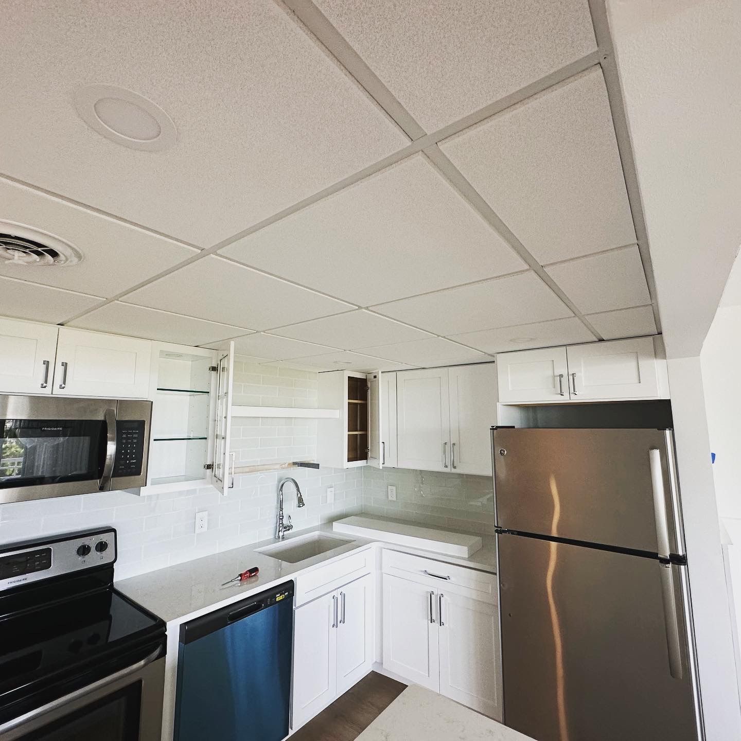 Kitchen with white cabinets, stainless steel appliances, and a tiled ceiling.