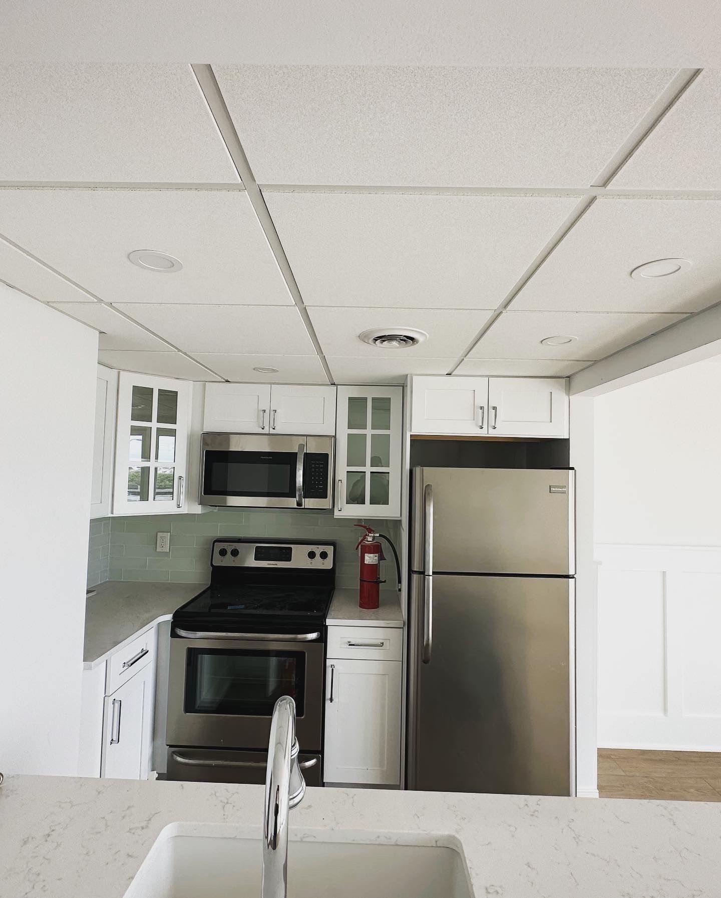 White kitchen with stainless steel appliances, white cabinets, and a white tile countertop.