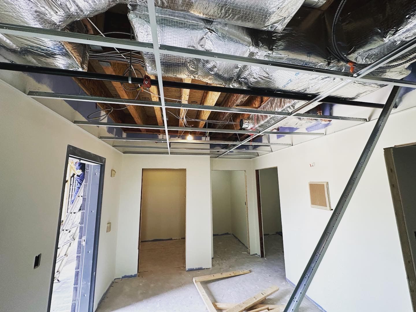 Unfinished ceiling with exposed beams and ductwork, multiple doorways.