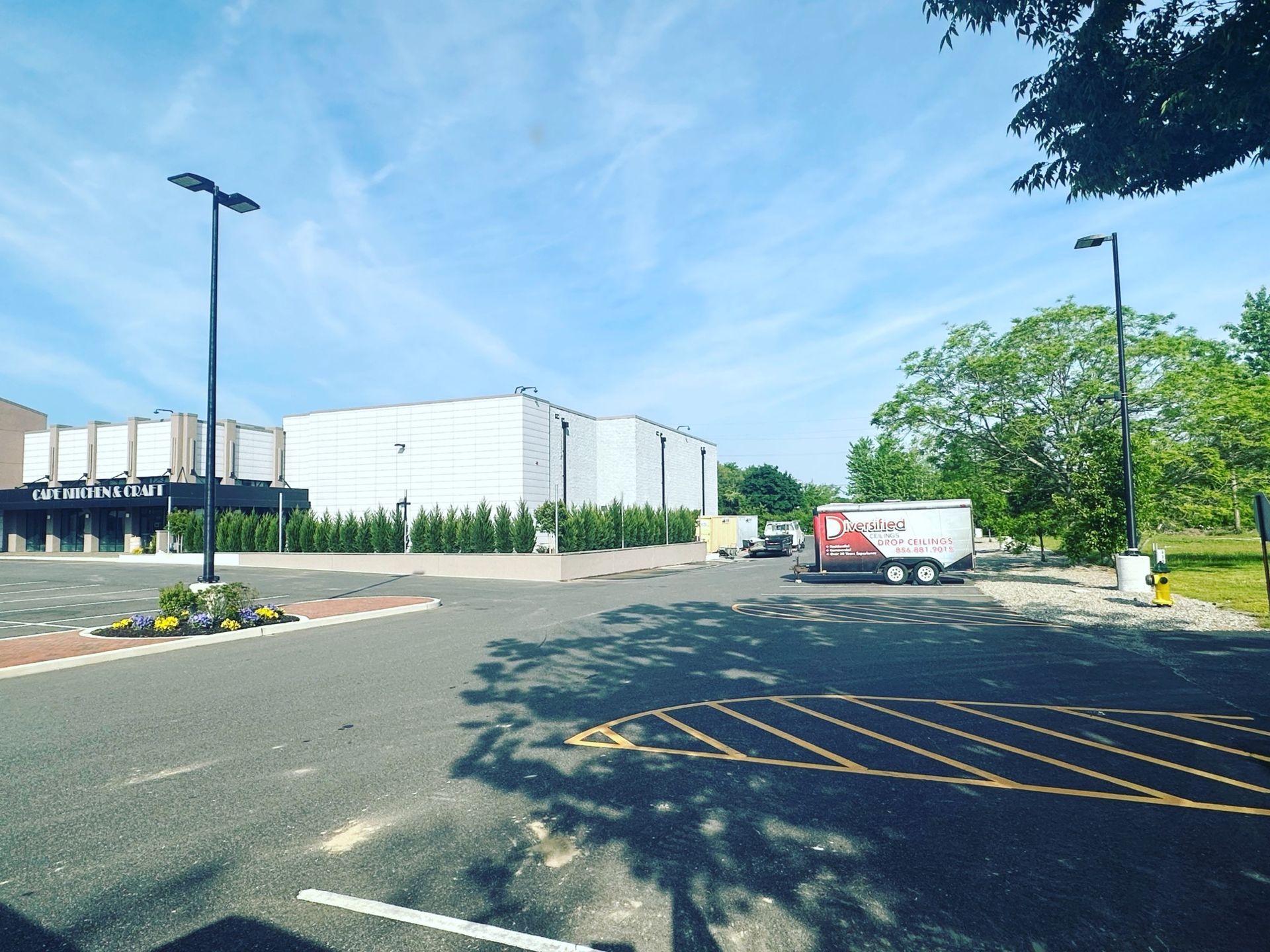 Building with columns, parking lot, trailer, trees, and blue sky.