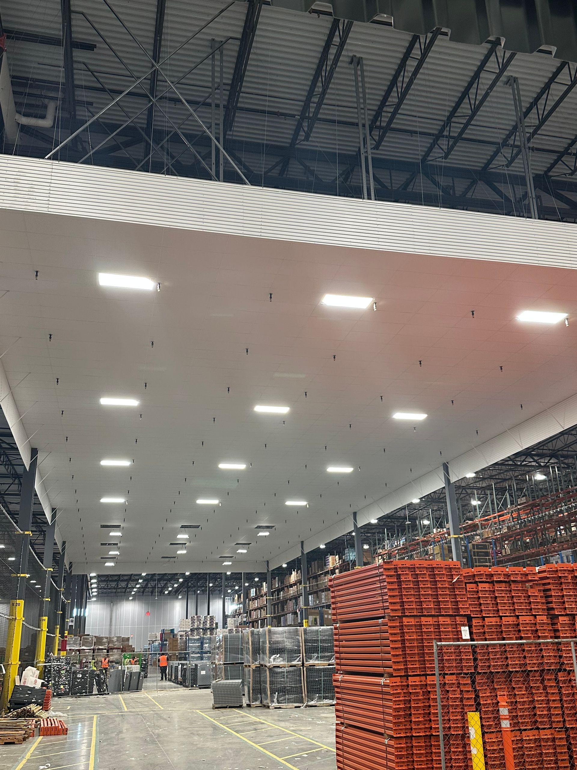 Large industrial warehouse interior with a suspended ceiling under construction.