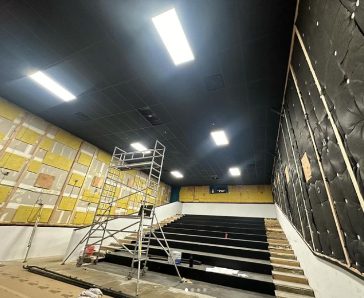 Interior of a cinema under construction with scaffolding and insulation.