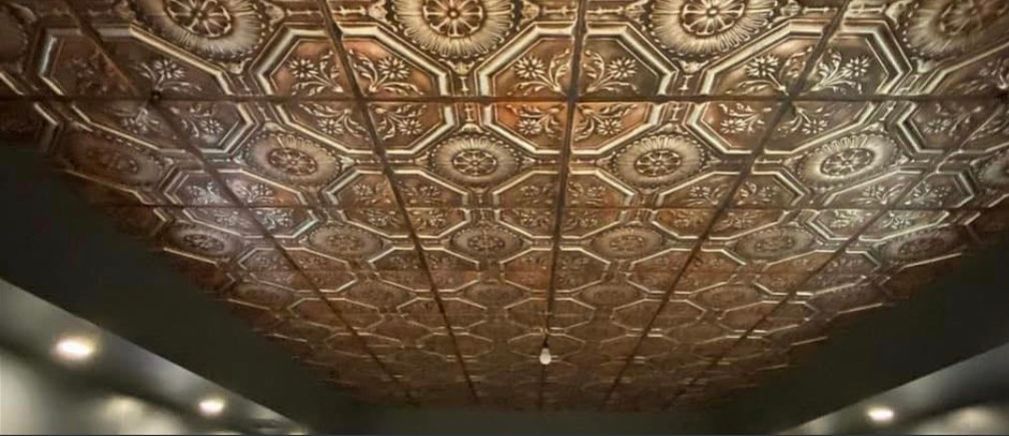 Close-up view of a decorative ceiling with ornate bronze tiles.