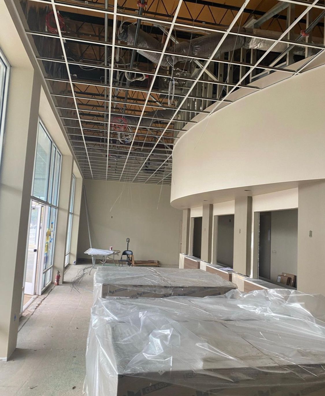 Interior construction: metal ceiling grid, curved wall, windows, covered counters, and open doorways.