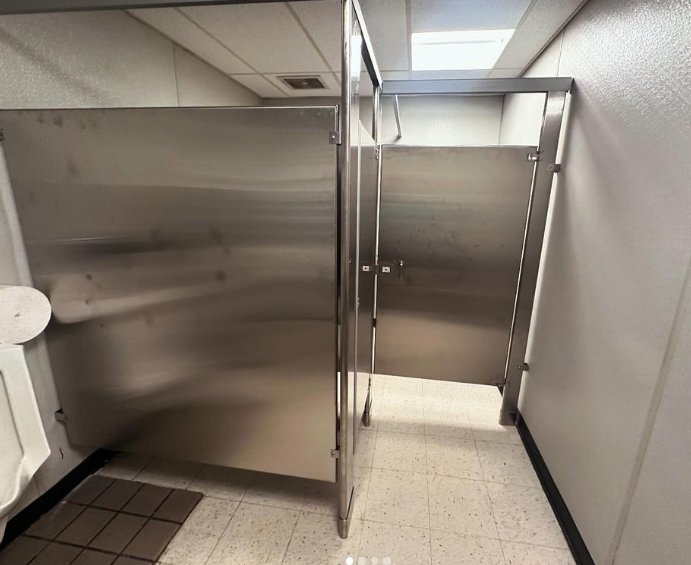 Two stainless steel bathroom stalls in a public restroom. Light and shadow create a contrast on the walls.