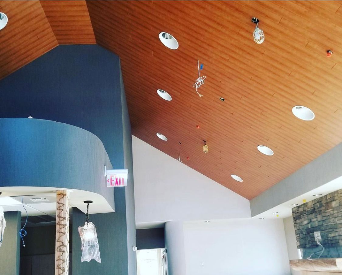 Interior view of a building under construction. Brown wooden ceiling with recessed lights, blue and white walls.