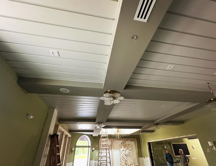 A gray and white paneled ceiling with recessed lighting and air vents. Olive-green walls.