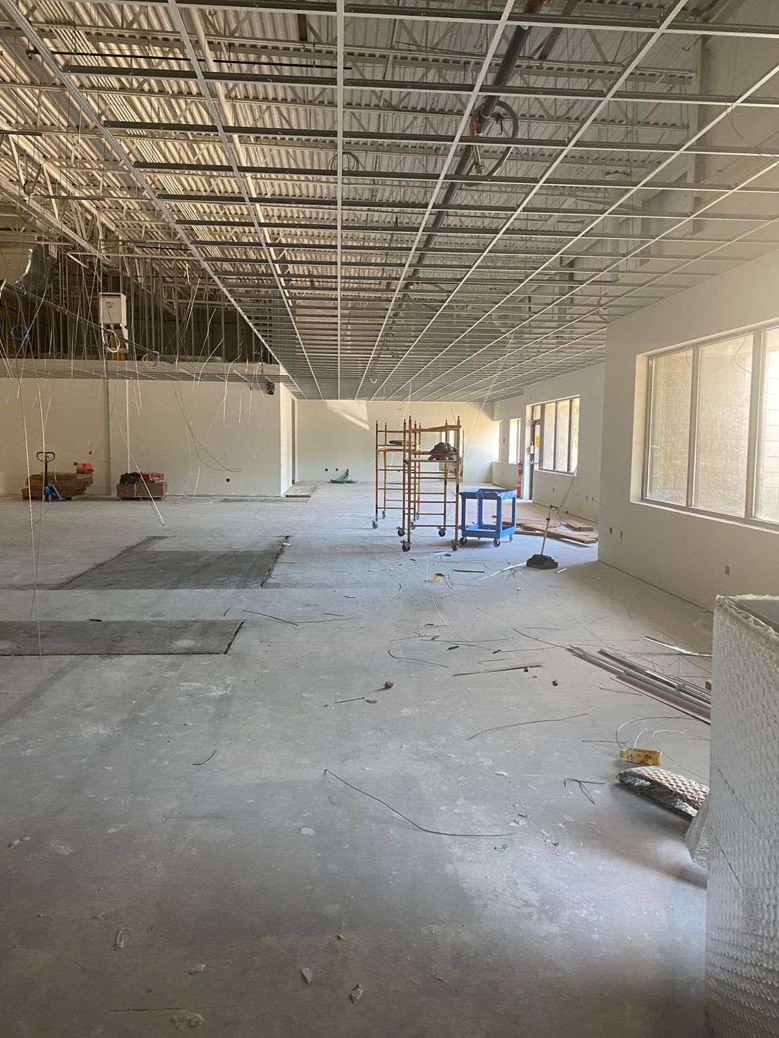 Construction site: interior view of a room with exposed ceiling grid, concrete floor, and unfinished walls.